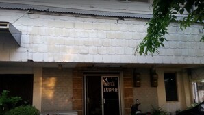 A hotel entrance with a tiled roof, a glass door, and a sign that reads "HOTEL INDAH". - Hotel Indah Syariah (Surabaya)
