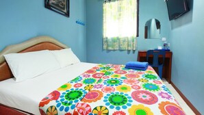 Un dormitorio con cama, escritorio, silla, televisor y ventana con cortinas.