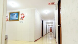 Un pasillo de hotel con un cartel que indica los números de habitación 316 al 328, una señal de salida y un cuadro con una cascada en la pared.