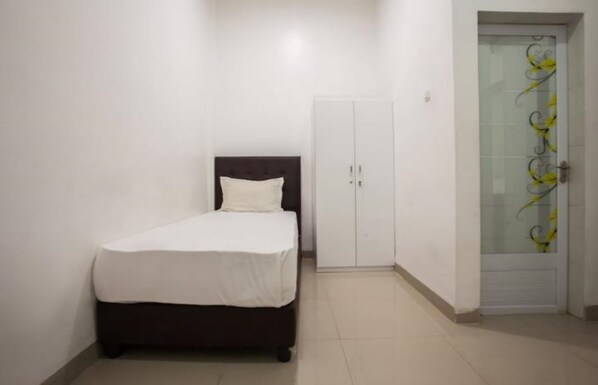 Un dormitorio con cama, armario y puerta con panel de vidrio decorativo.