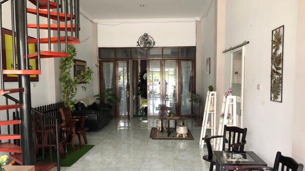 Amplia sala de estar con una escalera, una mesa de comedor con sillas y un sofá.