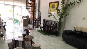 Amplia sala de estar con un sofá de cuero negro, una mesa redonda de centro con objetos decorativos y una escalera que sube a un nivel superior.