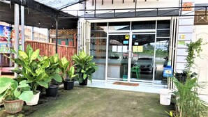 Un edificio con un patio techado, plantas en macetas y una entrada visible.
