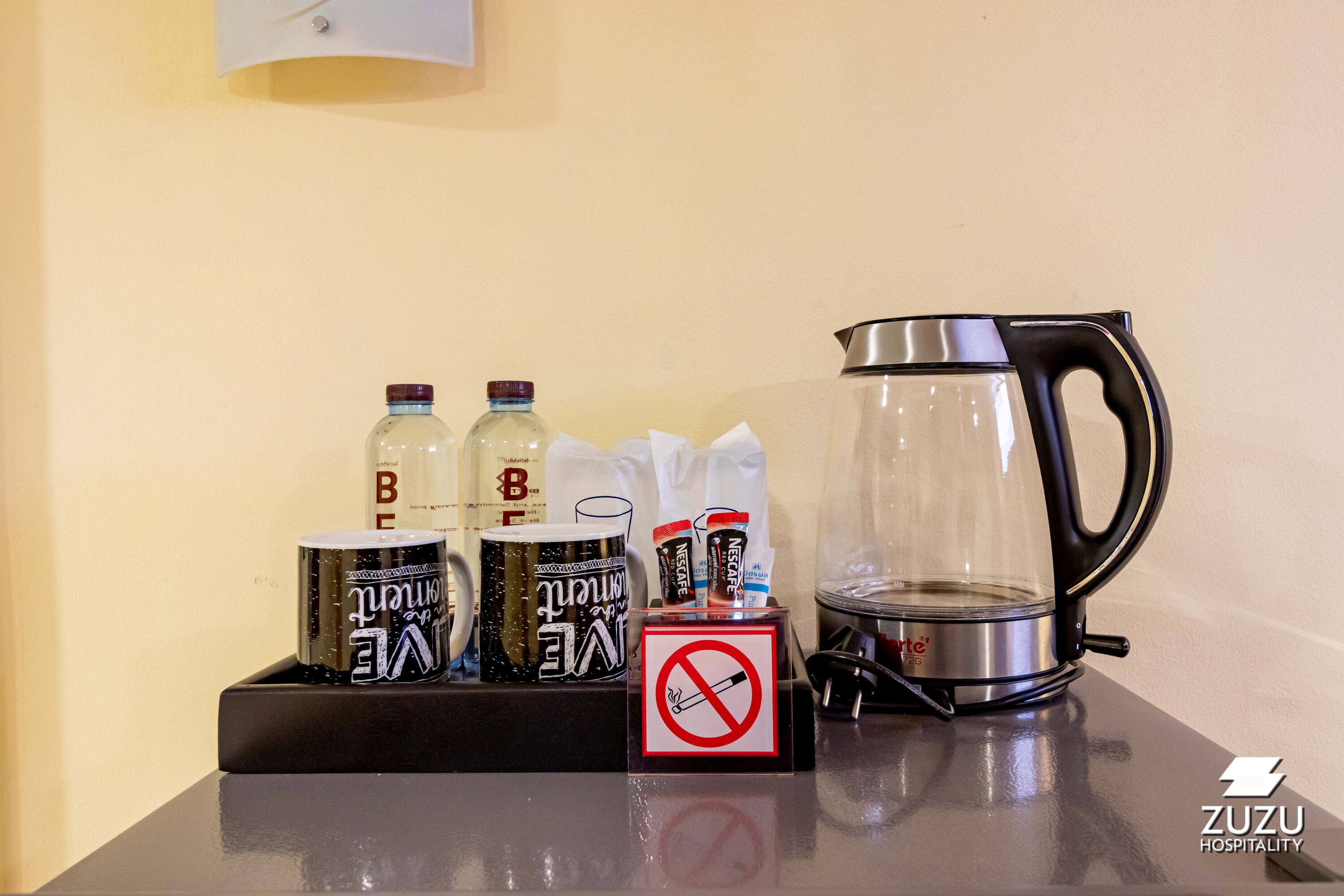 A tray with coffee mugs, a coffee pot, and a no-smoking sign on a hotel counter.