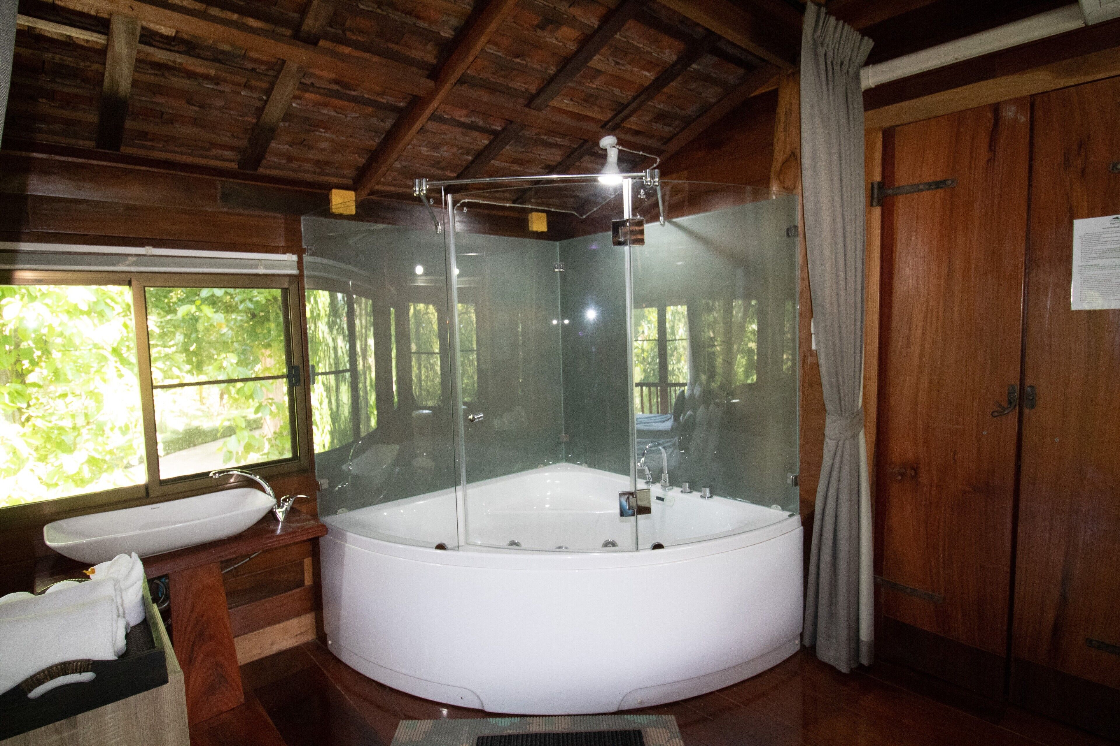 Un baño moderno con una bañera grande, ducha con cerramiento de vidrio y detalles de madera.