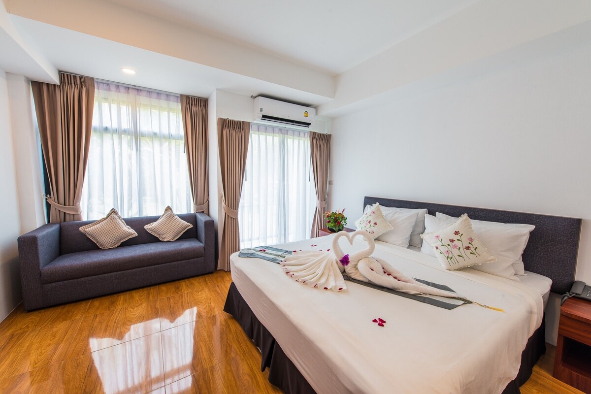 Een hotelkamer met een groot bed, een bank en een houten vloer.
