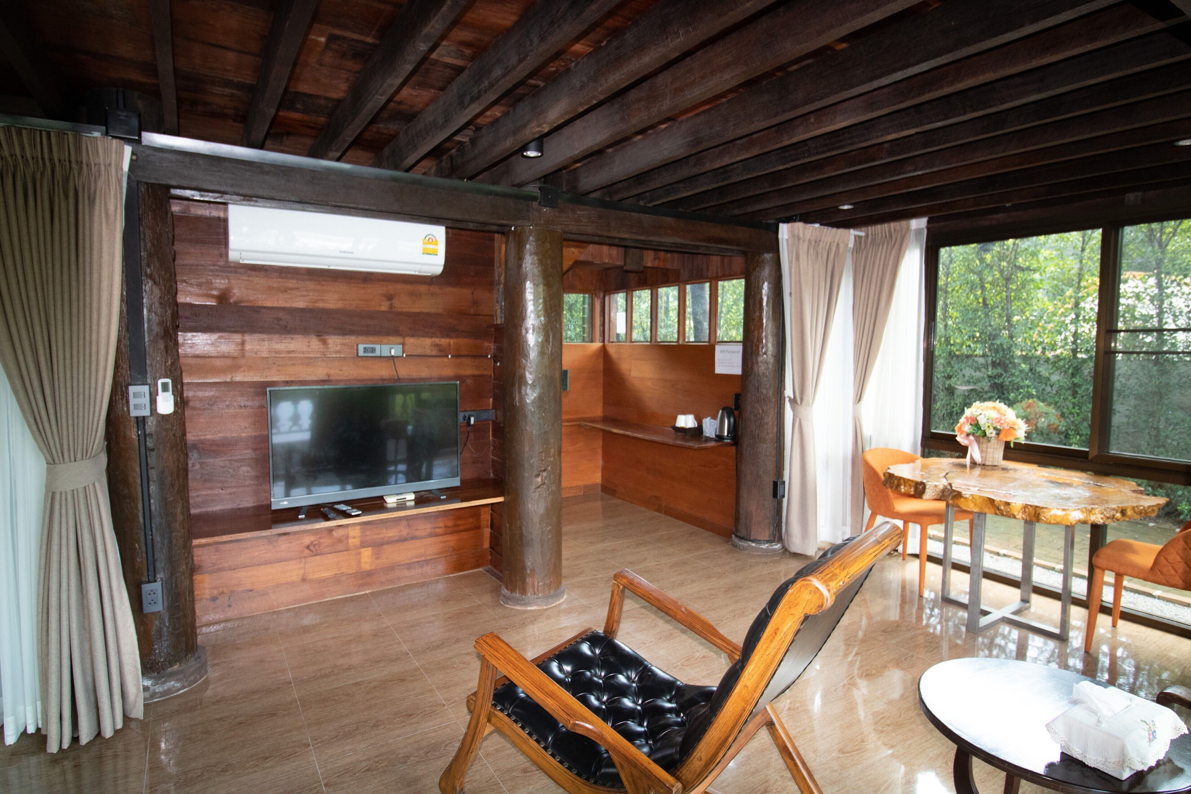 A wooden interior with a TV, seating, and a window with a view of trees.