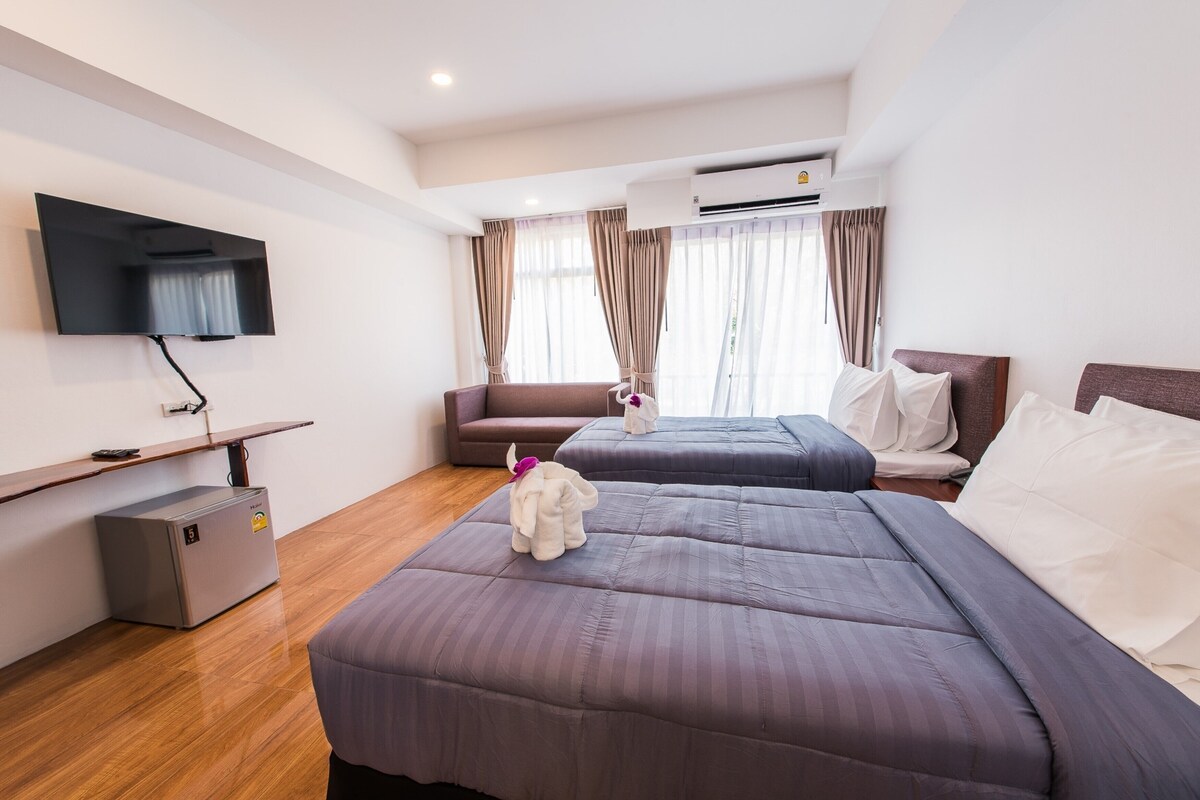Een hotelkamer met twee bedden, een televisie, een minibar en een airconditioner.