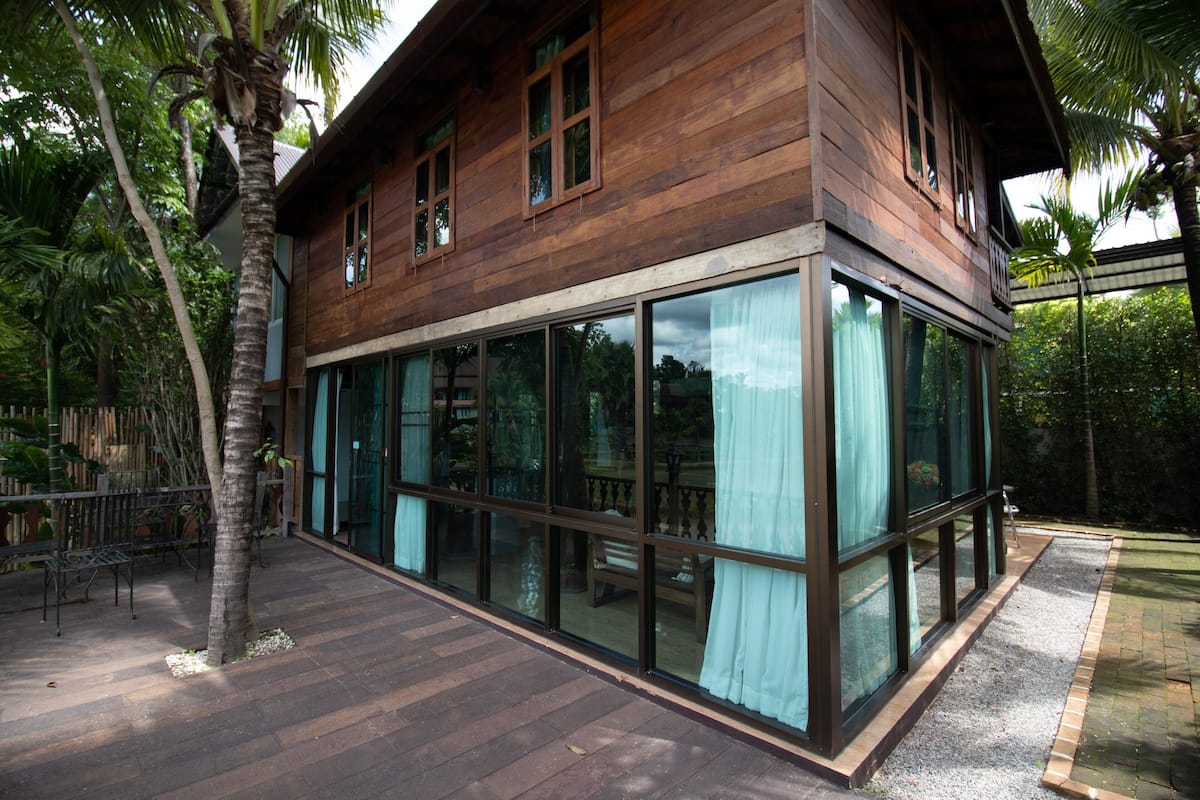 Een houten huis met grote glasramen en een houten terras.