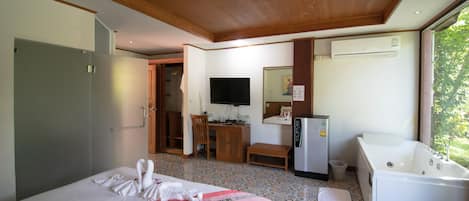 A hotel room with a bed, a desk, a TV, a mirror, a sink, and a bathtub.
