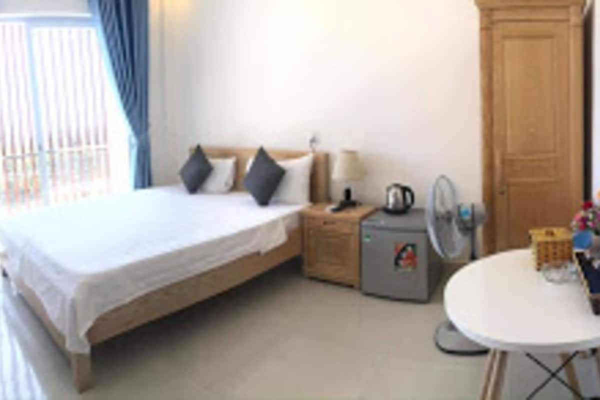 Une chambre à coucher avec un lit, une table de chevet, une lampe et une petite table sur laquelle sont posés divers objets.