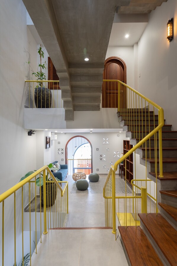 A multi-level interior with a staircase, a sofa, and decorative wall elements.
