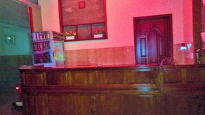A reception area with a wooden counter, a small shelf with items, and a door. - Cuc Phuong Hotel (Ho Chi Minh City)