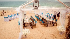 Ein Strand hochzeit Arrangement mit Tischen und Stühlen, unter einem Baldachin, mit Blick auf den Ozean.