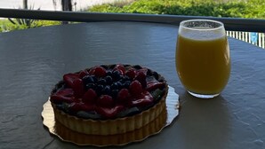 Un dolce con frutta su un tavolo con vista su una spiaggia e palme.