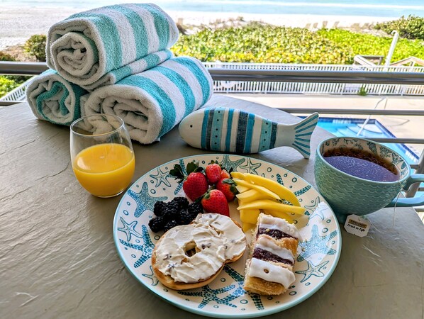 Una mesa con un plato de comida, un vaso de jugo de naranja, una taza y toallas dobladas.