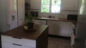 A kitchen with white cabinets, a wooden countertop, a window, and a refrigerator. - Love" guest room (Corcoué-sur-Logne)