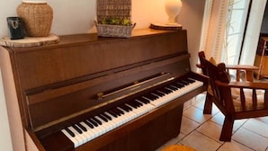 A piano in a room with a lamp, a wicker basket, and a small plant on the piano. - Love" guest room (Corcoué-sur-Logne)
