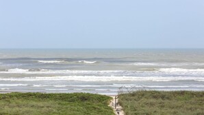 A coastal path leading to the sea with waves crashing onto the shore.