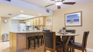 A kitchen with a central island, wooden chairs, and a dining table.