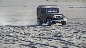 A vehicle driving on a sandy surface.