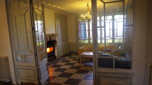 A room with a checkered floor, a fireplace, a sofa, and a table.