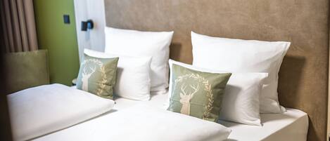 A hotel room with a bed, pillows, and a headboard.