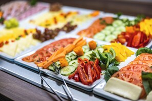 Een buffet met diverse soorten eten, zoals groenten, kaas en vlees.