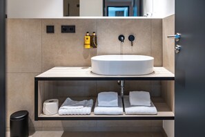 Un baño moderno con lavamanos redondo, toallero y artículos de aseo.