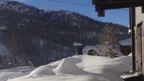 Un paysage enneigé avec un bâtiment en bois et un ciel dégagé.
