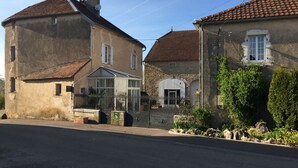 Un edificio de estilo europeo tradicional, con un invernadero, muros de piedra y tejado de tejas.