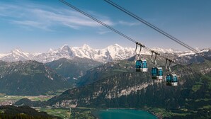 Un sistema de teleférico con un paisaje montañoso y un lago al fondo.