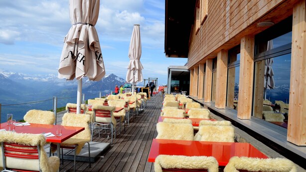 Un restaurante con terraza al aire libre que ofrece vistas a un paisaje montañoso.