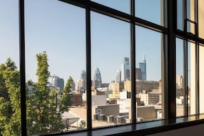 Vista a través de amplios ventanales de un paisaje urbano con diversos edificios, incluyendo un rascacielos distintivo.