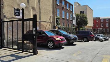 A gated parking area with multiple cars parked in front of a building with a 'Suite' sign.
