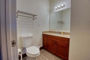 A bathroom with a toilet, sink, and mirror. - Sosuite | 1BR Apt w W/D, Gym, On-Site Restaurant (Philadelphia)