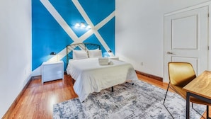 A bedroom with a bed, bedside tables, a chair, and a door. - Sosuite | 2BR Apt w W/D, Gym, On-Site Restaurant (Philadelphia)