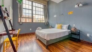 A bedroom with a bed, a desk with a chair, a window, and a lamp. - Sosuite | 2BR Apt w W/D, Gym, On-SIte Restaurant (Philadelphia)