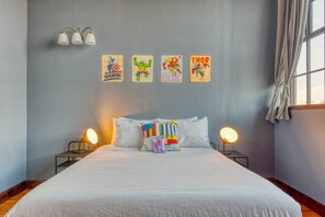 Un dormitorio con una cama grande, dos lámparas de noche y cuatro pósters de superhéroes colgados en la pared.