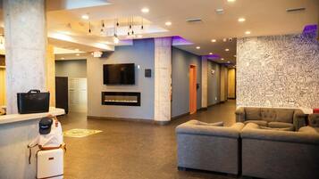 A lobby with a reception desk, a flat-screen TV, a fireplace, and a seating area.