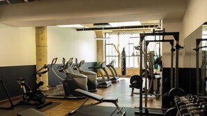 A gym with exercise equipment, including treadmills, stationary bikes, and weight machines. - Sosuite | 2BR Apt w W/D, Gym, On-Site Restaurant (Philadelphia)