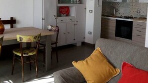 Espaço compacto com área de refeições, cozinha compacta e sofá com almofadas.