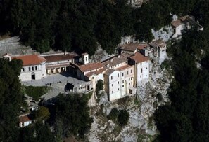 Vista aèria d'un conjunt arquitectònic històric amb diverses edificacions, envoltat per un bosc dens.