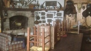 Um quarto rústico com lareira, móveis de madeira e diversos utensílios e decorações nas paredes.