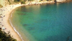 A coastal beach with clear turquoise waters and a rocky cliff in the background. - Blue view, blue bay, lerici (lerici)
