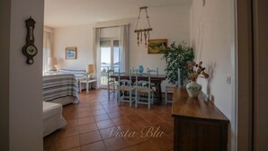 A room with a bed, a desk, a chair, a dining table, and a plant. - Blue view, blue bay, lerici (lerici)