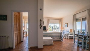 A hotel room with a bed, a small table, a chair, a window with curtains, and a view of the outdoors. - Blue view, blue bay, lerici (lerici)