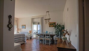 Quarto com cama, escrivaninha, cadeira, mesa de jantar e planta.