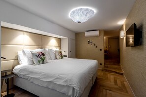 Une chambre d’hôtel moderne dotée d’un grand lit, d’une table de chevet, d’un téléviseur fixé au mur et d’un luminaire au plafond au design original.