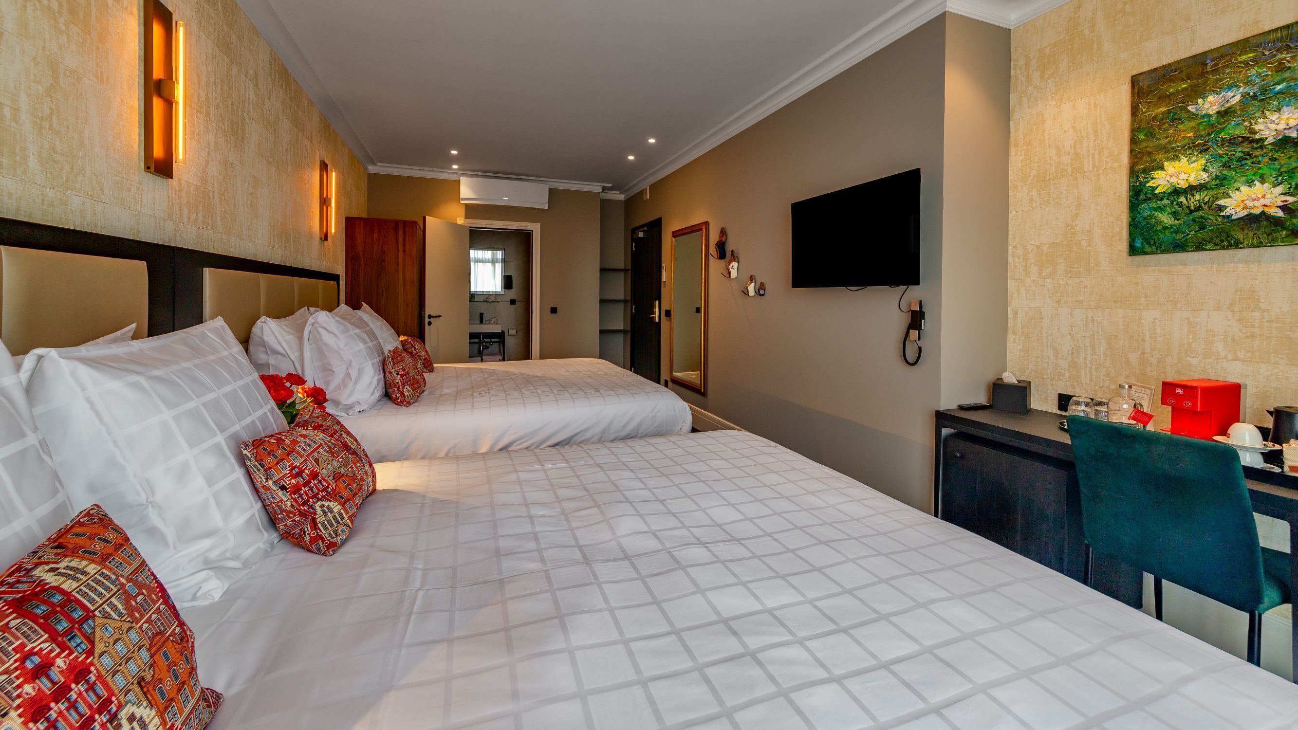 Una habitación de hotel con dos camas, un escritorio, un televisor y un cuadro en la pared.